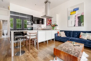 A modern kitchen with a central island, bar stools, and a dining area. - Luxury Central London 2 x double bed apartment - Hampstead (London)