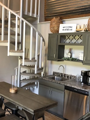 Una cucina con piano cottura integrato, lavello e zona pranzo con tavolo e sedie.