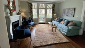 Een woonkamer met een open haard, een bank, een salontafel en een vloerkleed.
