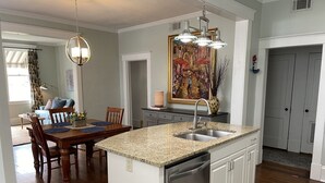 Een keuken met een granieten aanrecht, een roestvrijstalen spoelbak en een vaatwasser. Er is een eethoek met een houten tafel en stoelen.