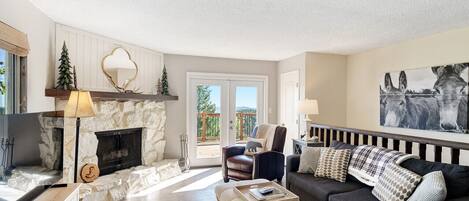 A living room with a stone fireplace, a sofa, a coffee table, and a large painting on the wall.