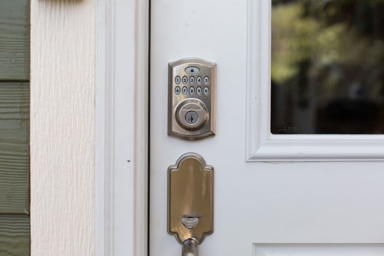Una puerta con teclado numérico y un llamador de latón.
