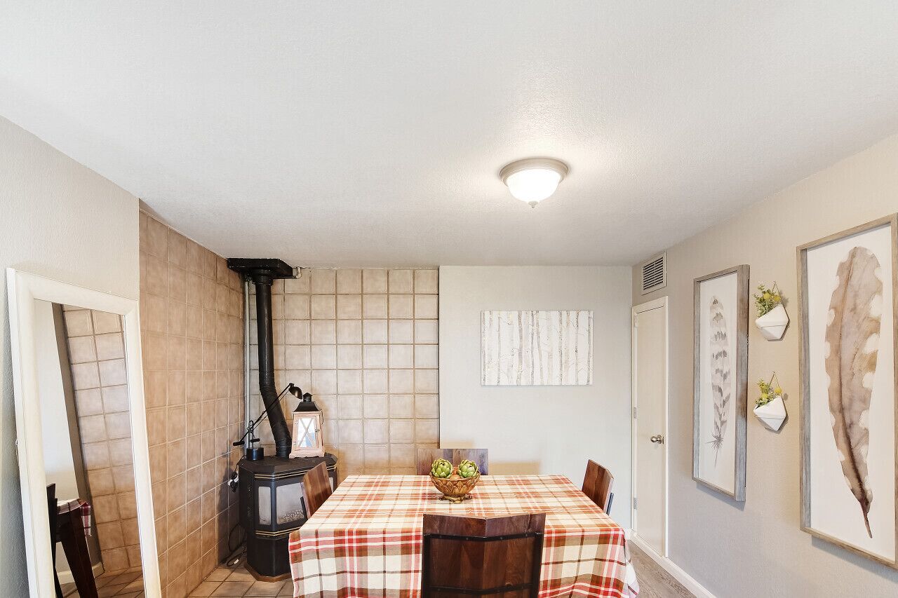Un comedor con una mesa preparada para cuatro personas, un estufa de leña y una pared de azulejos.