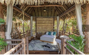 Cozy retreat with a single bed, patterned rug, and lush greenery outside.
