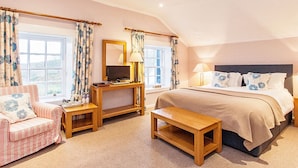 A bedroom with a large bed, a desk, a chair, and a small table. - The Colonsay Hotel (Isle of Colonsay)