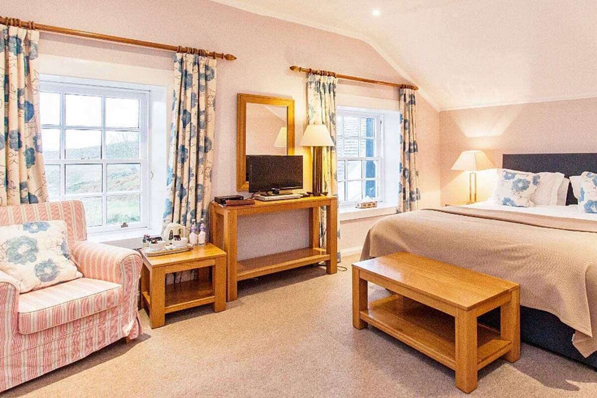 A bedroom with a large bed, a desk, a chair, and a small table.