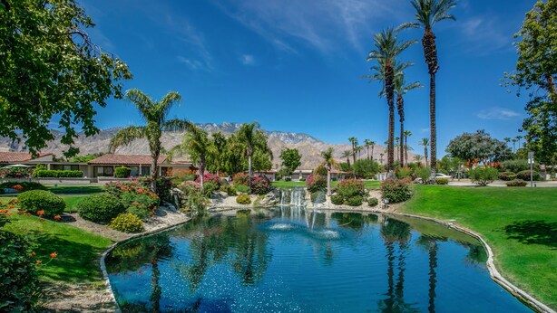 A swimming pool with a waterfall, surrounded by lush greenery and palm trees. - Winter with us in beautiful sunny Palm Springs! (Palm Springs)
