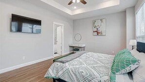 Ein Schlafzimmer mit einem Bett, Deckenventilator und einem großen Fenster.
