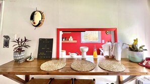 A wooden table with woven placemats, a potted plant, and a vintage red telephone.