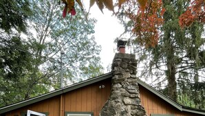 A cabin with a stone chimney, wooden exterior, and a welcoming sign.