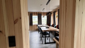 A modern dining area with a wooden interior, a long table with chairs, and a view through a window. - Bergquell Willingen App. 4 (Willingen)