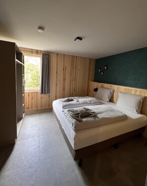 Ein Schlafzimmer mit Bett, Kleiderschrank und einem Fenster mit Vorhängen.