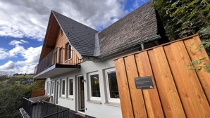 A modern two-story building with a balcony, large windows, and a wooden fence. - Bergquell Willingen App. 4 (Willingen)