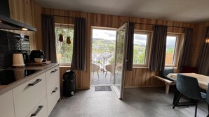 A modern kitchen with a dining area, large windows, and a view of the countryside. - Bergquell Willingen App. 4 (Willingen)