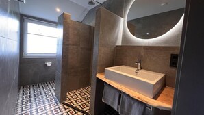 A modern bathroom with a large mirror, a sink, and patterned floor tiles. - Bergquell Willingen App. 6 (Willingen)