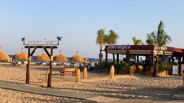 A beach scene with a sign reading "Morabito Beach" and a restaurant named "Worabitto." - 1 minute to the beach! Family-sized Garden and BBQ (Miami Platja)
