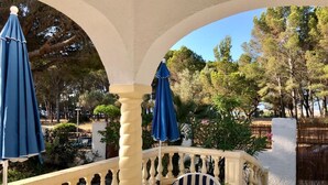 A balcony with a table, chairs, and blue umbrellas. - 1 minute to the beach! Family-sized Garden and BBQ (Miami Platja)