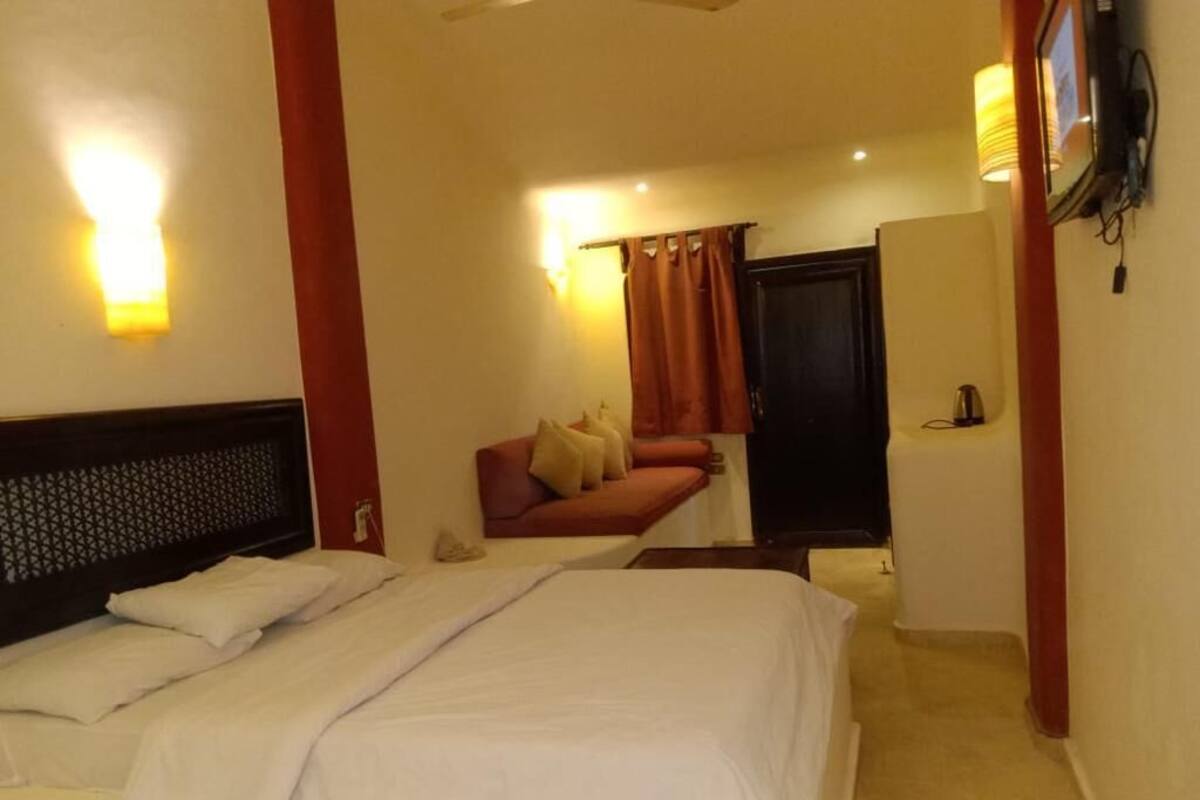 A hotel room with a large bed, a sofa, a desk, and a mirror.