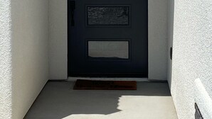 A modern black door with four rectangular glass panels, set in a white stucco wall. - The Perfect Lake Havasu Lake View Pool/Spa Home getaway!!! (Lake Havasu City)