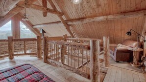 Une cabane en bois rustique avec une chambre à l’étage, un escalier en bois et un canapé en cuir.