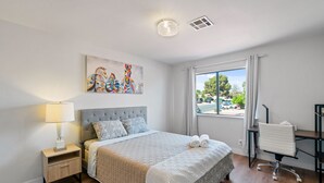 Une chambre moderne avec un grand lit, un bureau et une fenêtre donnant sur la rue.