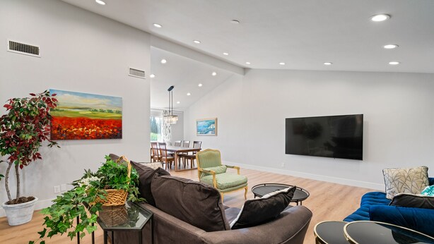 Un salon moderne avec un canapé, un fauteuil bleu, une petite table et un téléviseur fixé au mur.