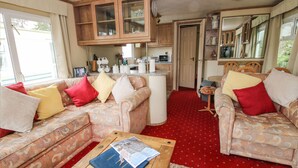 A compact living space with a sofa set, a coffee table, and a kitchen area. - 10 Old Orchard (Much Wenlock)