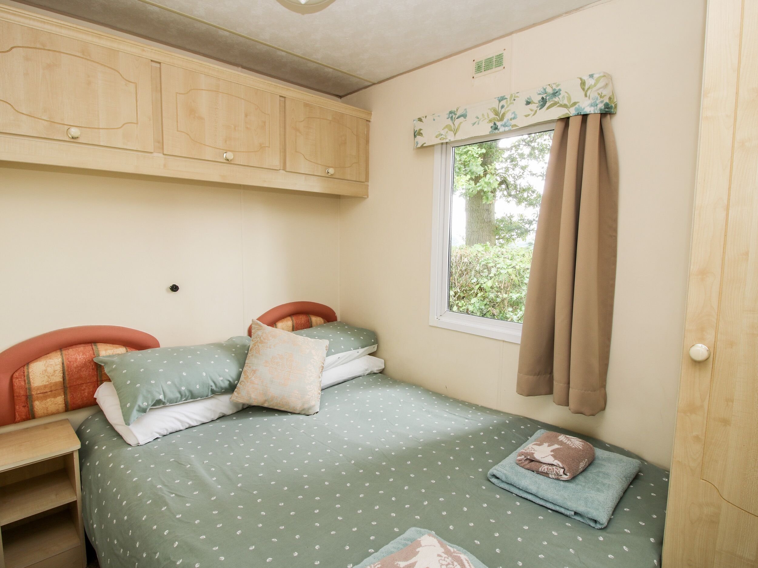 Une petite chambre à coucher, chaleureuse et accueillante, avec un lit simple, une armoire en bois et une fenêtre avec des rideaux.