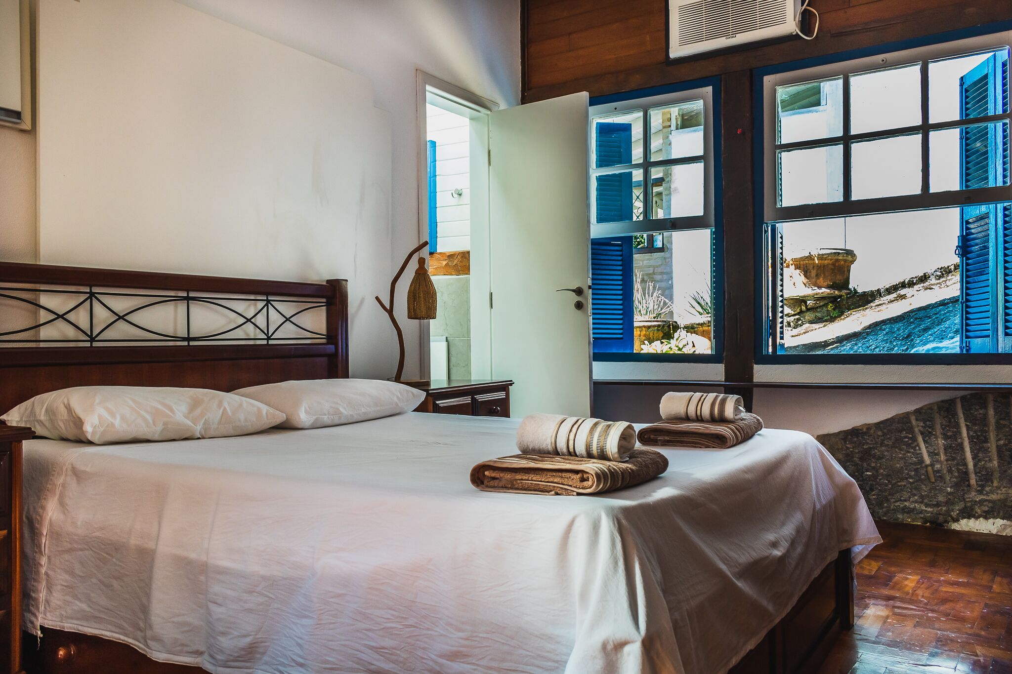 A neatly made bed with pillows, a wooden headboard, and a window with a view of a building and snowy landscape.