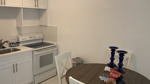 Ett kök med vita skåp, en spis och ett matbord med blå stolar.