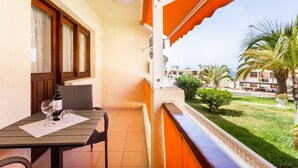 Een balkon met een tafel, stoelen en een fles wijn.