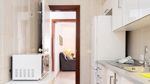 Een moderne keuken met witte kastjes, een inbouwmagnetron en een eethoek met een tafel en stoelen.