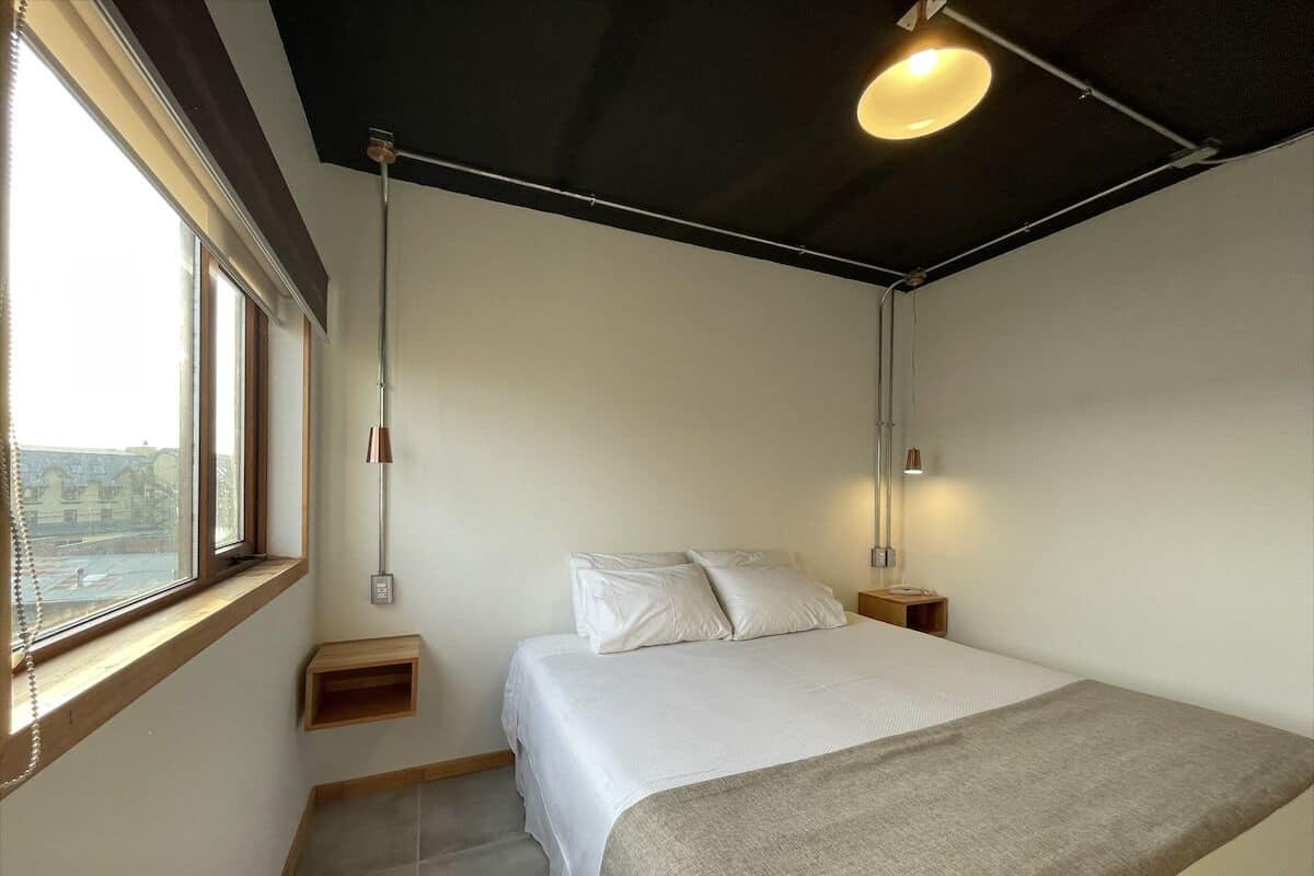 A bedroom with a bed, bedside tables, a window, and a ceiling light fixture.