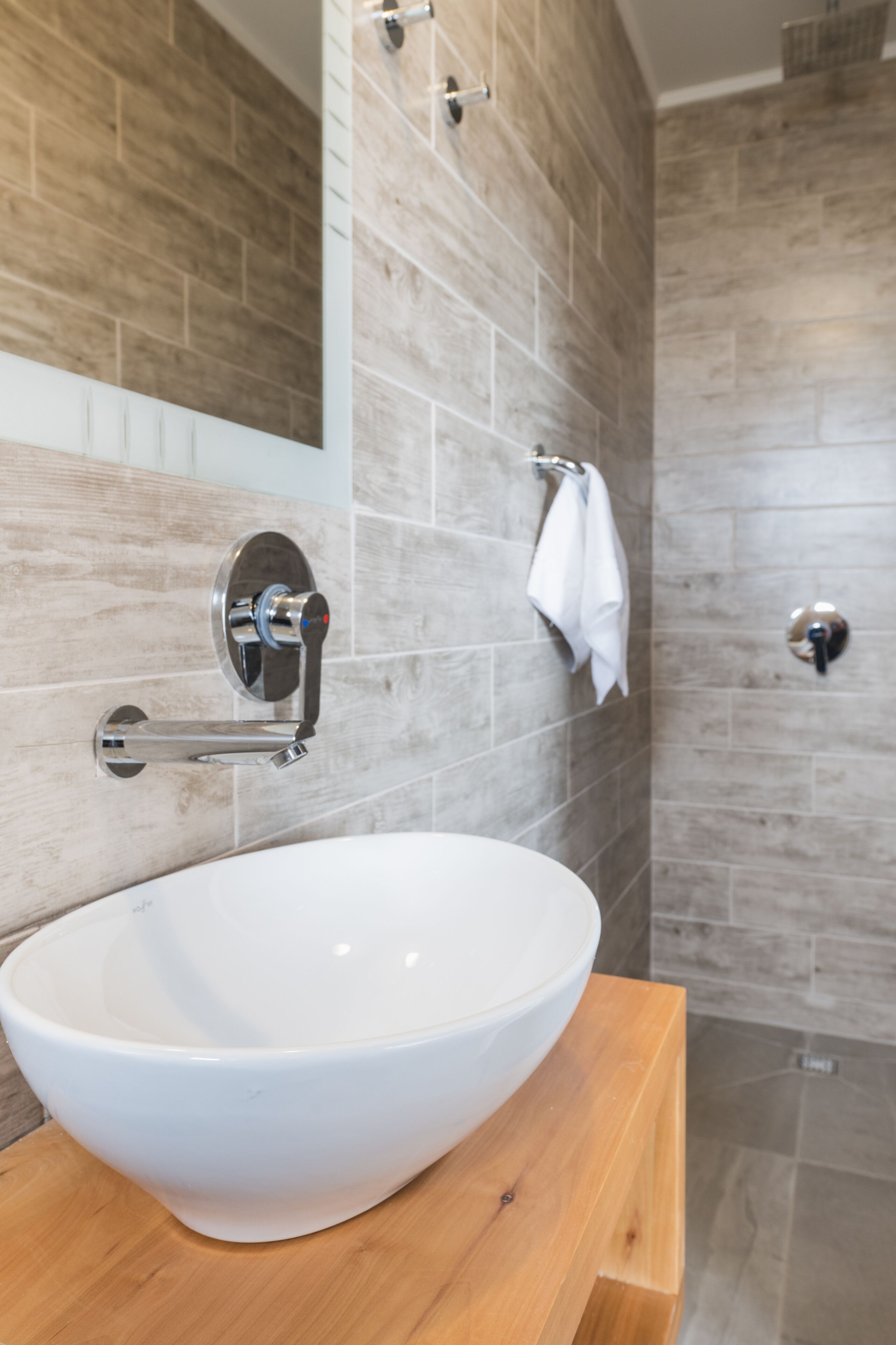 A bathroom with a white sink, wooden vanity, and a mirror.