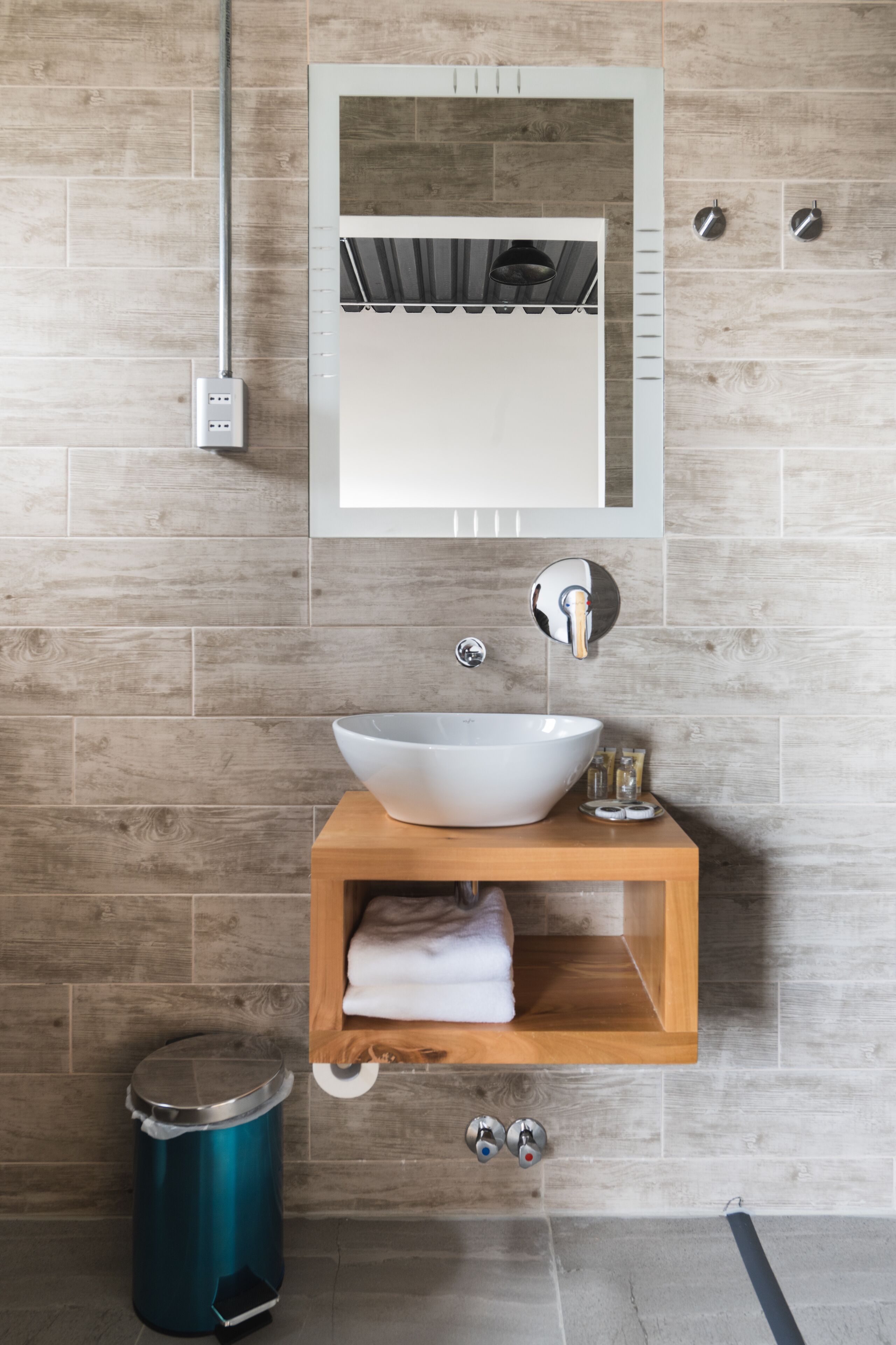 Un bagno moderno con un mobile vanitario in legno, un lavandino bianco e uno specchio sopra.