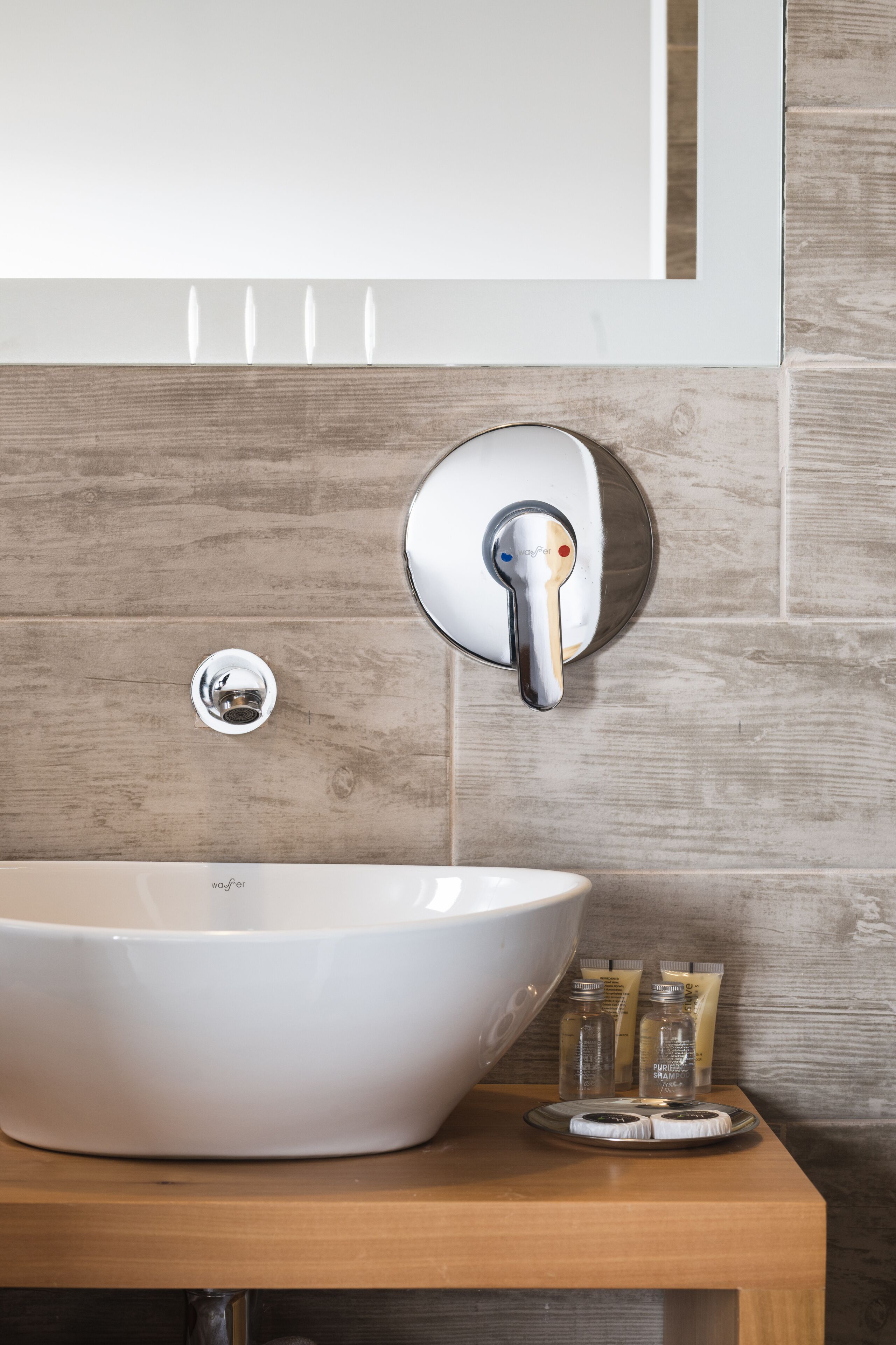 A bathroom with a white vessel sink, a chrome faucet, and a wooden vanity.