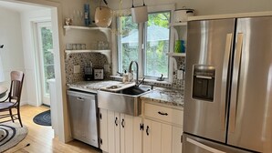 Uma cozinha moderna com eletrodomésticos de aço inoxidável, painel de parede de pedra e janela com vista para o exterior.