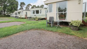 A caravan park with multiple caravans, outdoor seating areas, and a gravel path. - 2 Old Orchard (Much Wenlock)