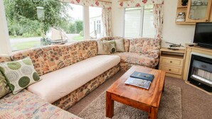 A cozy living room with a sofa, a wooden coffee table, and a television.