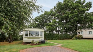 A mobile home with a small garden area and a gravel driveway.