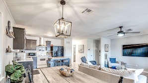 Una cocina moderna con armarios oscuros, una isla central y un comedor con mesa y sillas de madera.