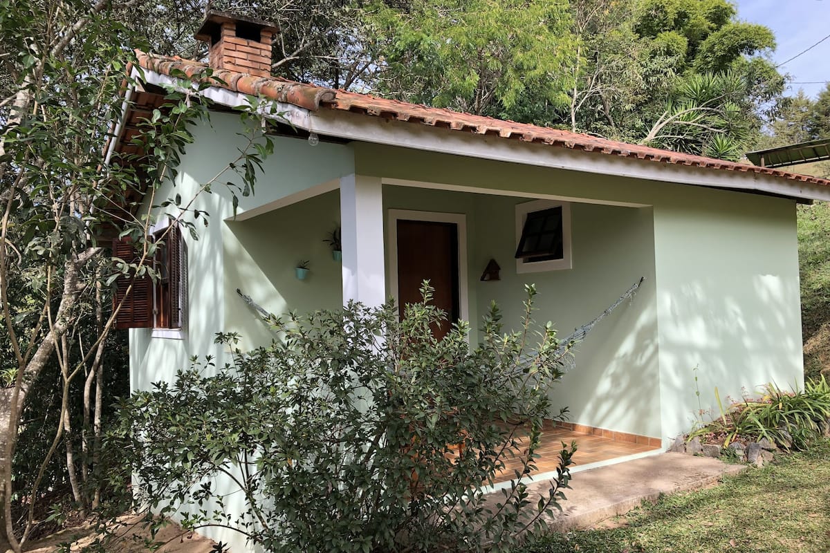 Una casa pequeña de una sola planta con techo de tejas, porche y puerta.