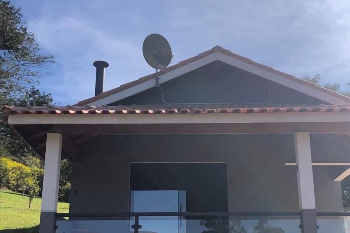 Una casa moderna con antena parabólica, un ventanal grande y un porche cubierto.