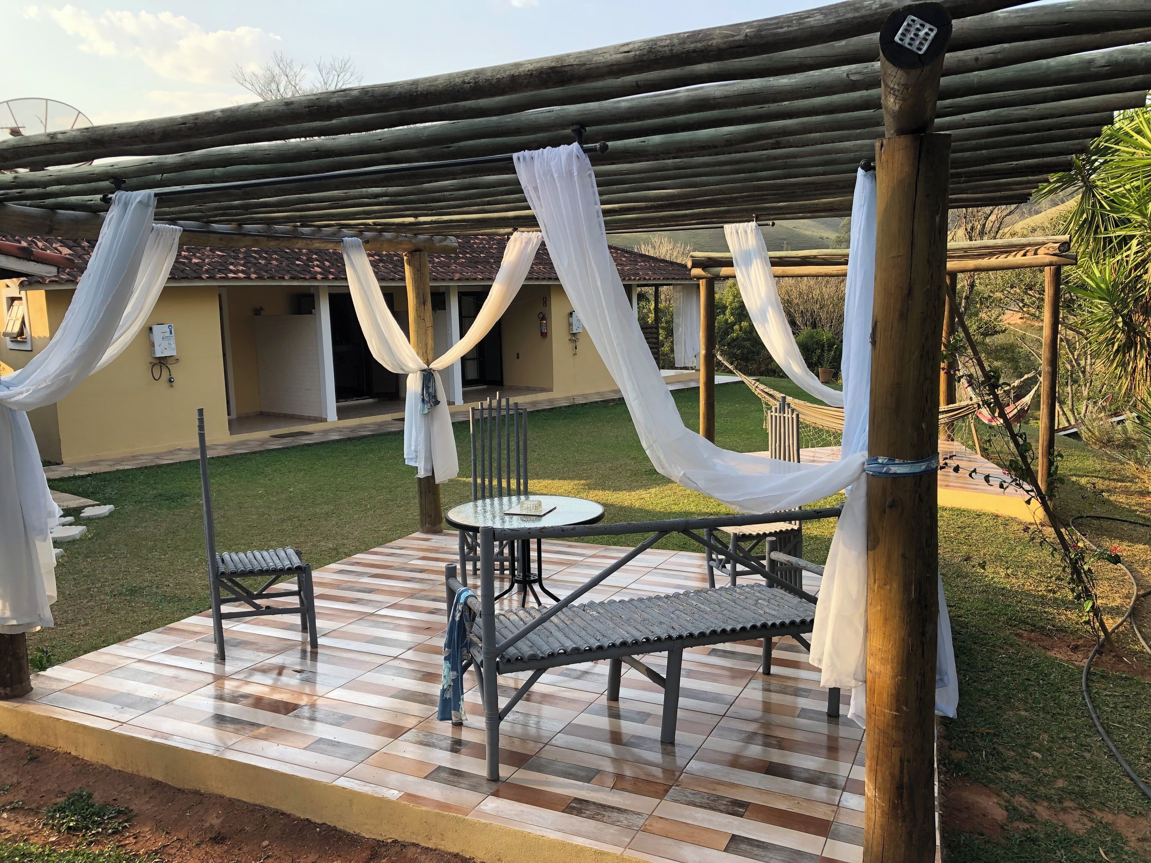 Un espace extérieur abrité, aménagé avec une table et des chaises, le tout recouvert d’un tissu blanc.