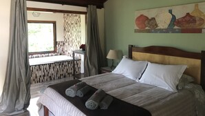 Un dormitorio con cama, ventana, un cuadro y un baño a la vista.