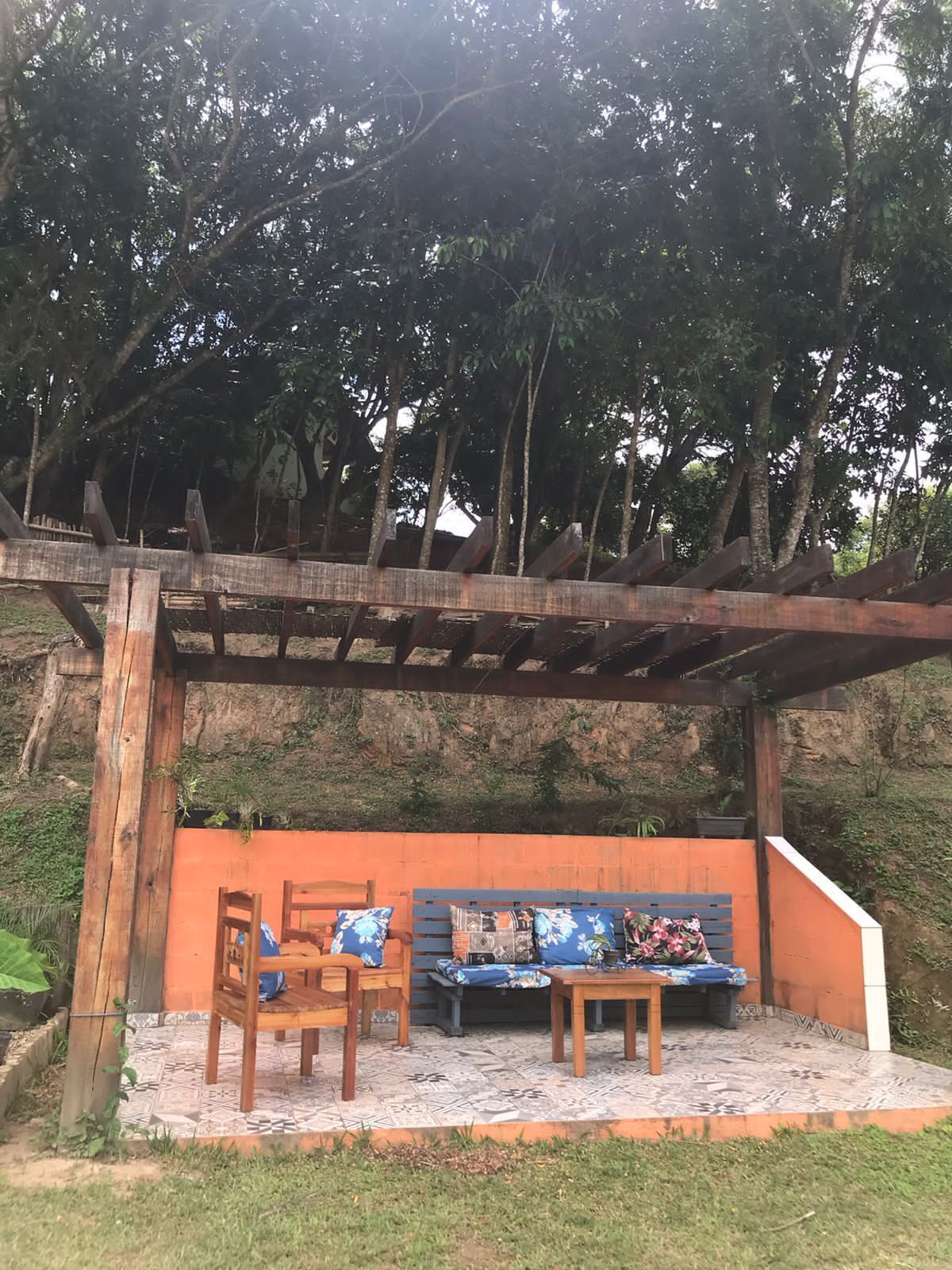 Un área de estar al aire libre con muebles de madera y una pérgola.