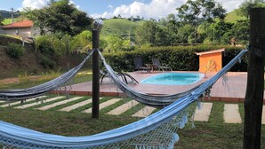 Una hamaca en un patio trasero con piscina y un pequeño edificio.