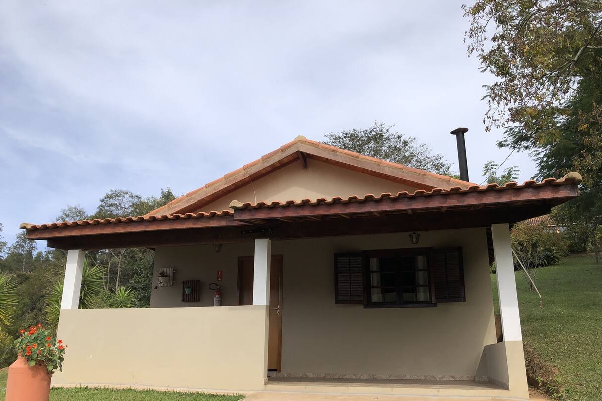 Una casa de un piso con techo de tejas, un porche y un pequeño jardín.