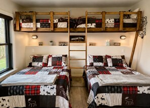Ein Zimmer mit zwei Betten, einem Schlafpodest und einer Leitern.