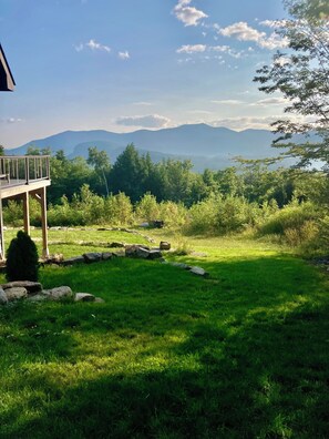A grassy outdoor area with a wooden deck and a mountain view.